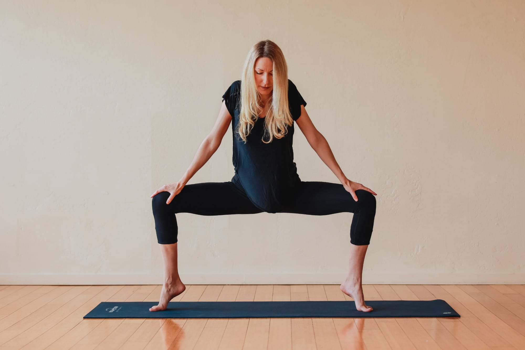 Kara standing in a wide-legged yoga pose